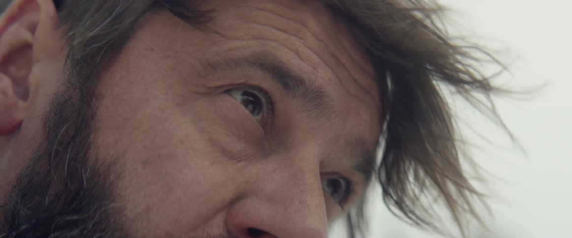 Man's face looking down as the wind blows his hair