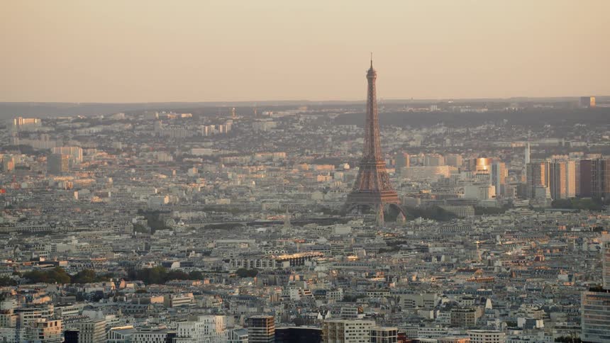 The eiffel tower stands tall above the other city buildings near the canal