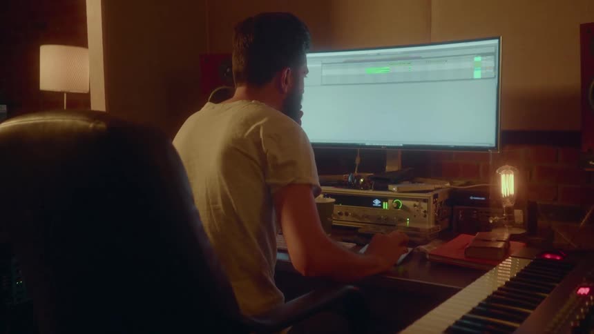 A man is editing music in a studio