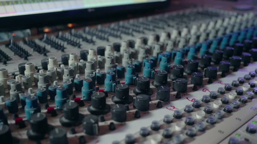 Knobs sit on a mixing board in a recording studio