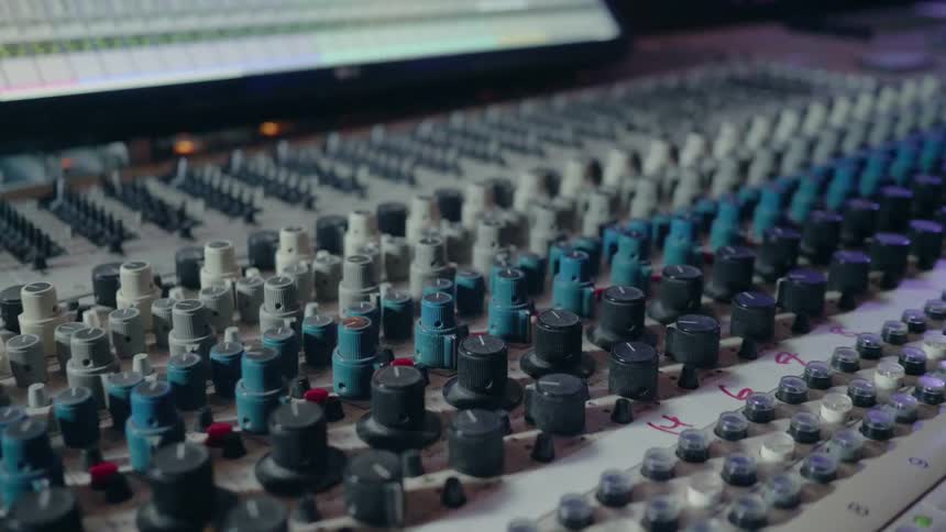 Knobs sit on a mixing board in a recording studio