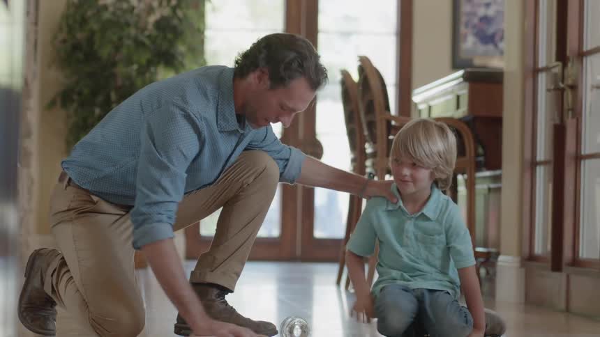 A little boy spilled a glass of water and his father is helping clean it up