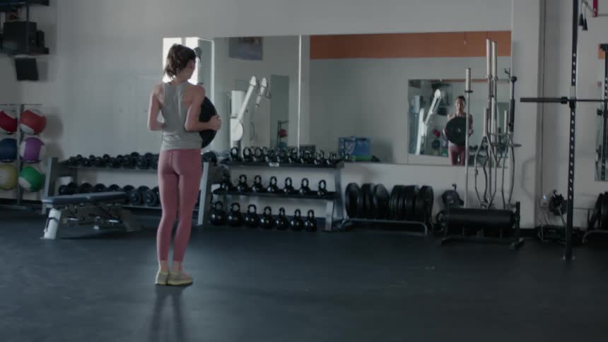 Woman exercises doing lunges while holding a large disc