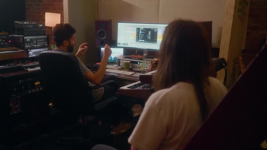 Musicians sit in a studio and talk to each other