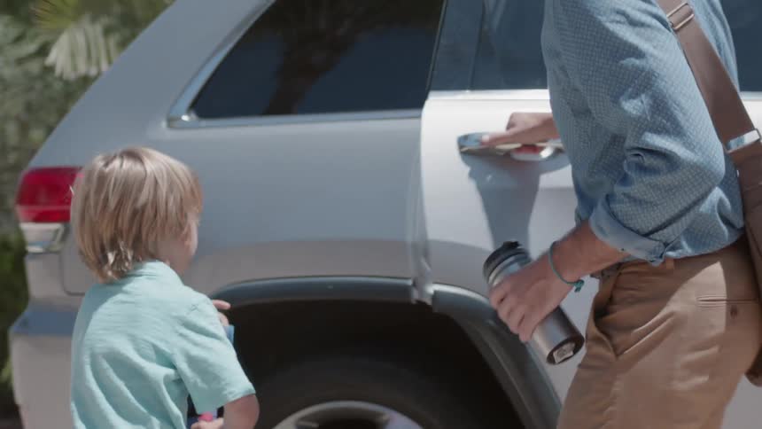 A man leads a young boy to a car