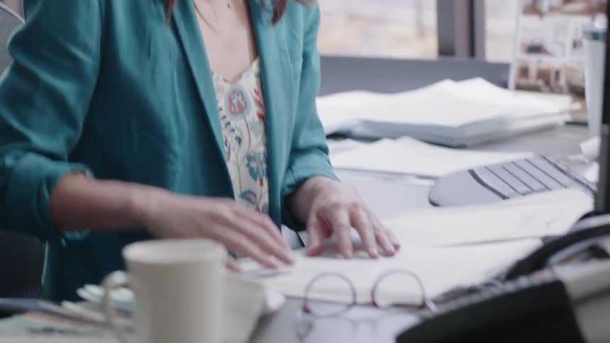 A business woman places her glasses down on a desk