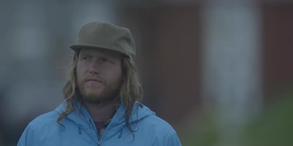 Bearded man in hat and blue jacket looks around