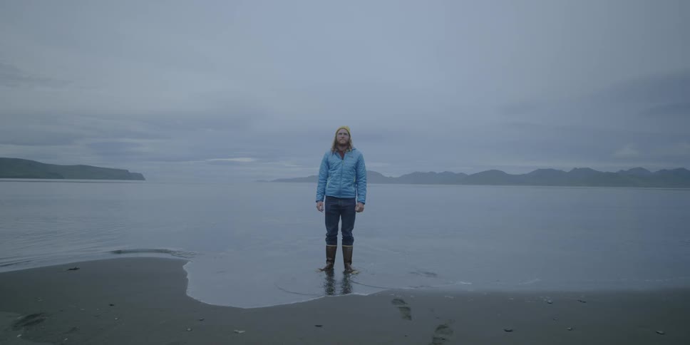 A man stands ankle deep in the water