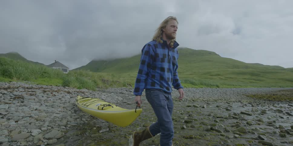 A man drags a kayak on a beach