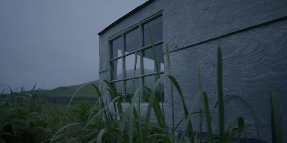 A small wooden cabin surrounded by grass