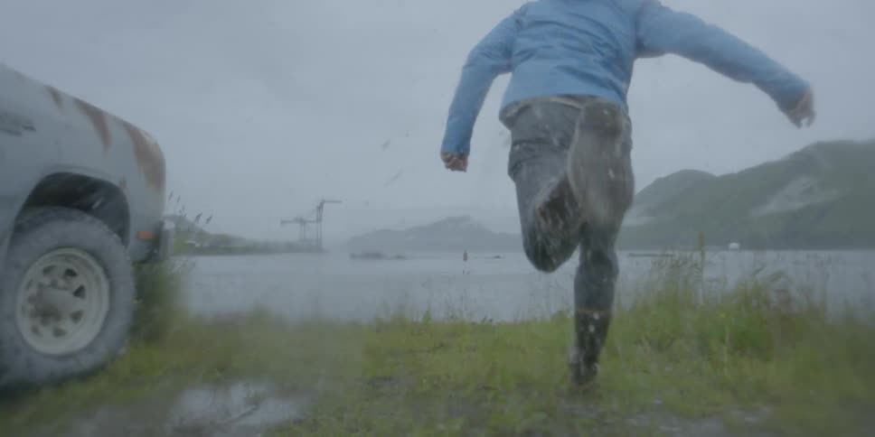 Man in boots splashes in a puddle and runs towards ocean