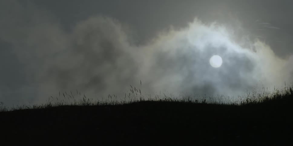 Clouds float over a grassy field