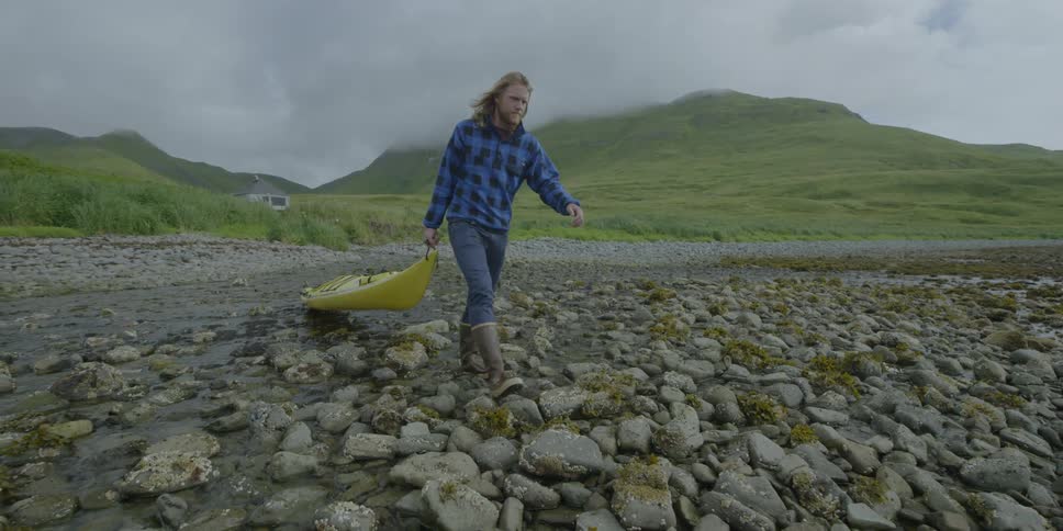 A man drags a kayak on the beach