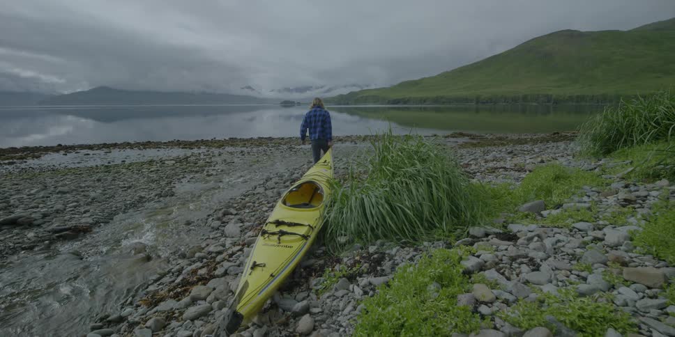 A man pulls a kayak towards the water