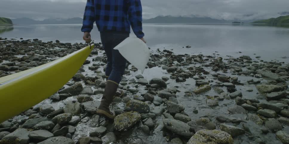 A man pulls a kayak towards the water