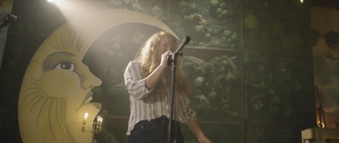 Woman sings into a microphone on stage