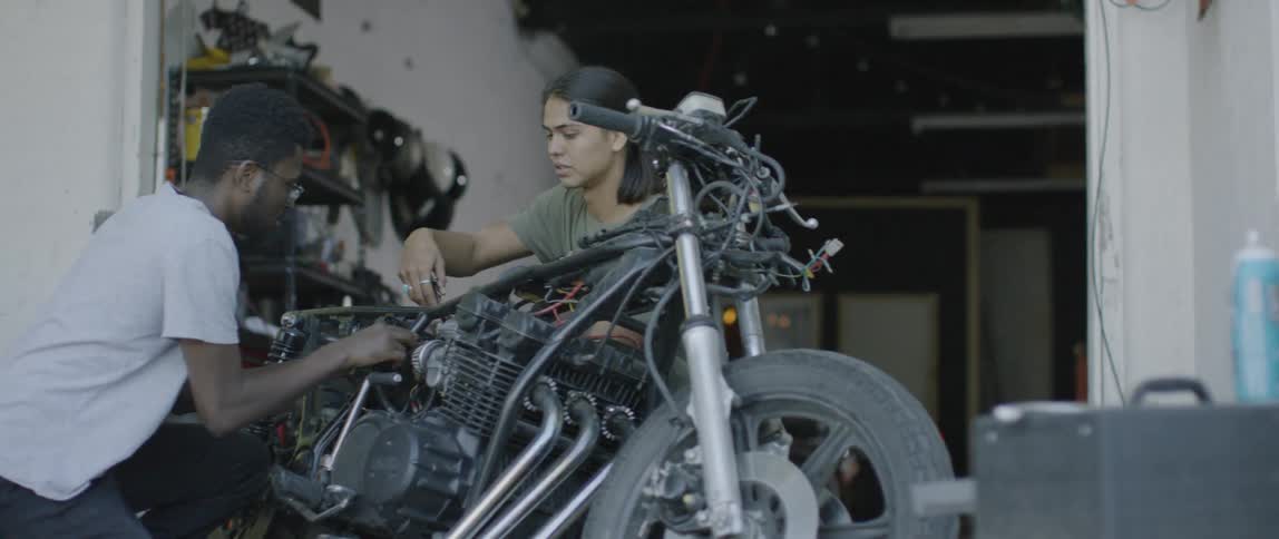 Two men work on a motorcycle in a garage