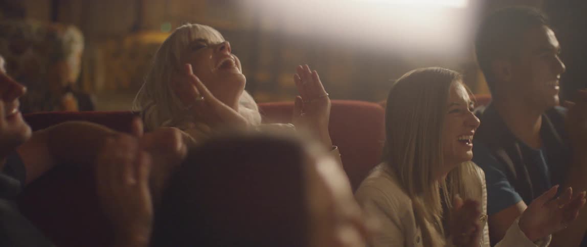 A group of people dance and laugh on a couch
