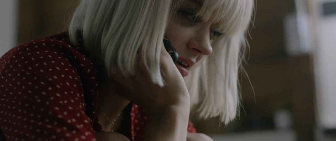 A woman sits curled up while talking on the phone