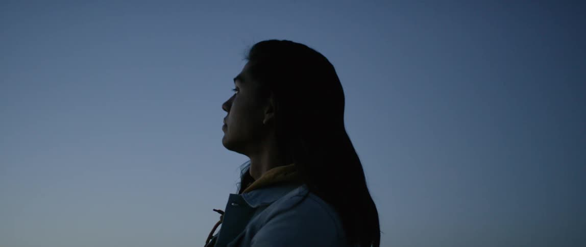 A long-haired person looks at the sky