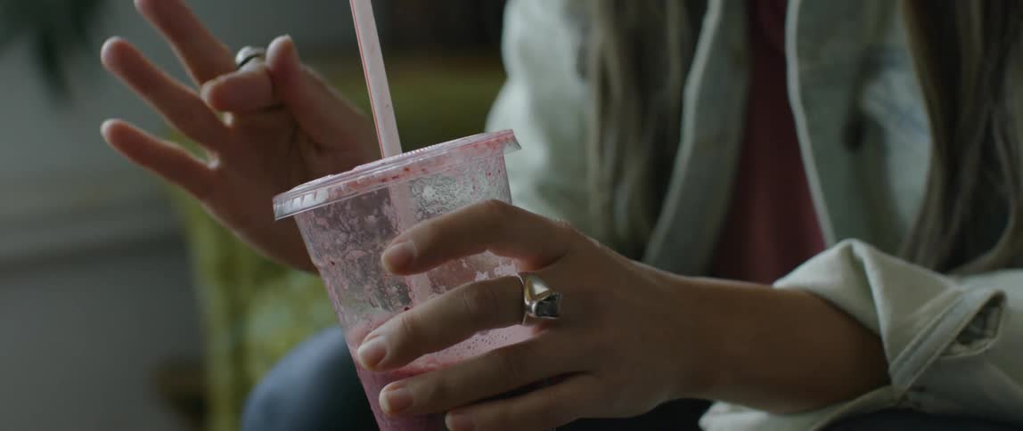 A woman talks and sips from a smoothie