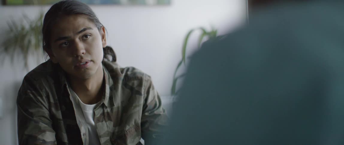 A young man is speaking indoors