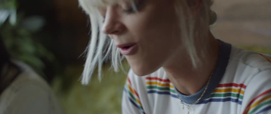 A blond woman laughs while drinking through a straw