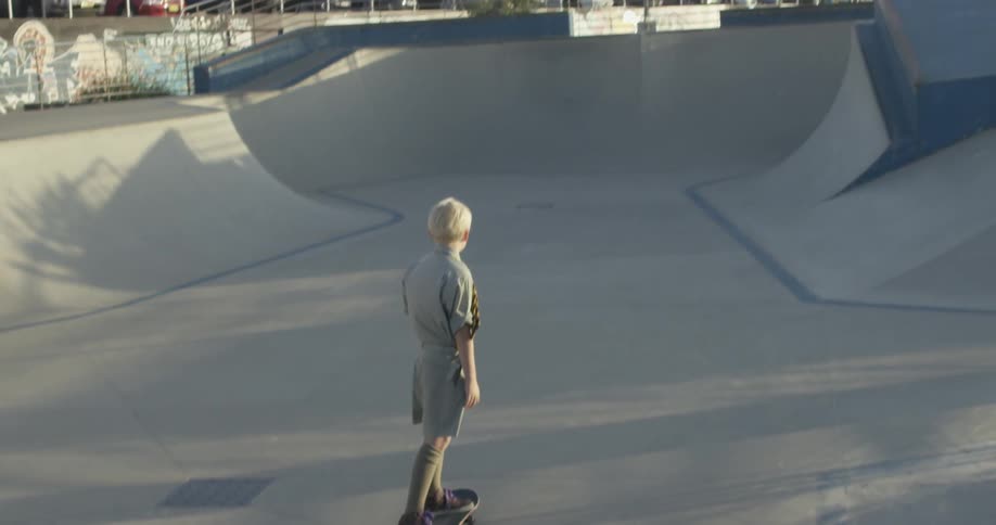 Child wearing a tie skateboarding at a park