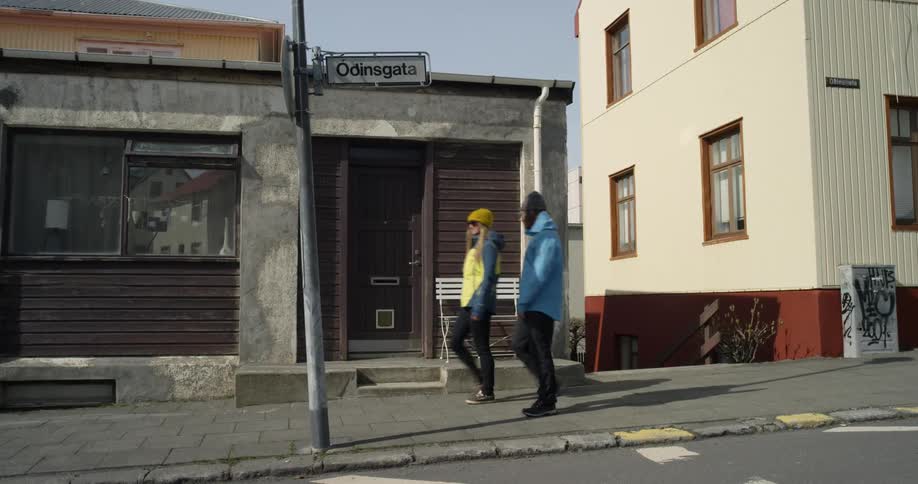 Two people walk past the buildings on the sidewalk