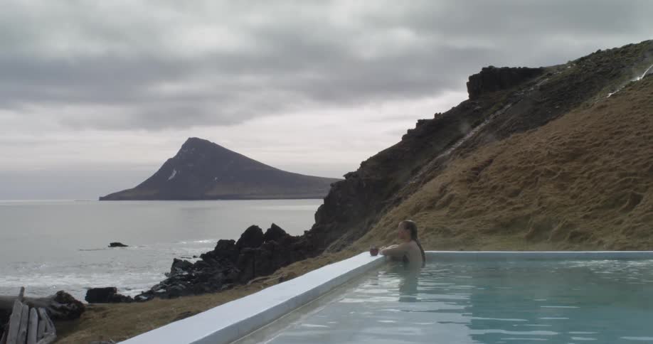 A person sits in a pool by the shore