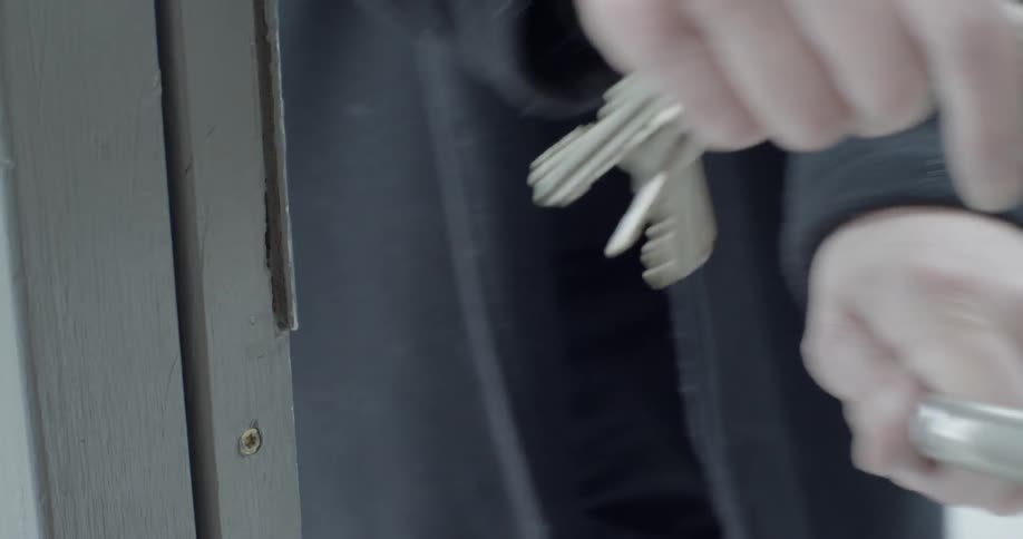 A person opens a locked door with keys from the outside and walks in