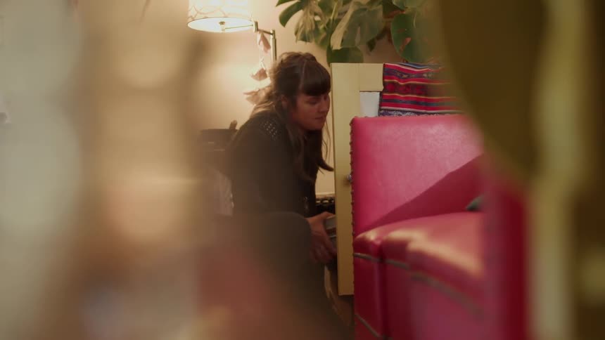 A woman looks inside a cabinet and grabs binders from it