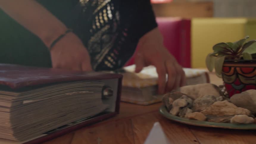 A woman is setting a photo album on a coffee table and leafing through it