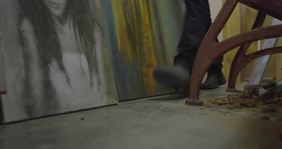 Someone is walking past a bunch of paintings resting on the ground