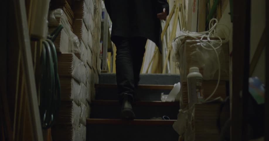 A man walks up dark stairs