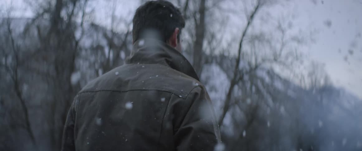 A man is walking through falling snow