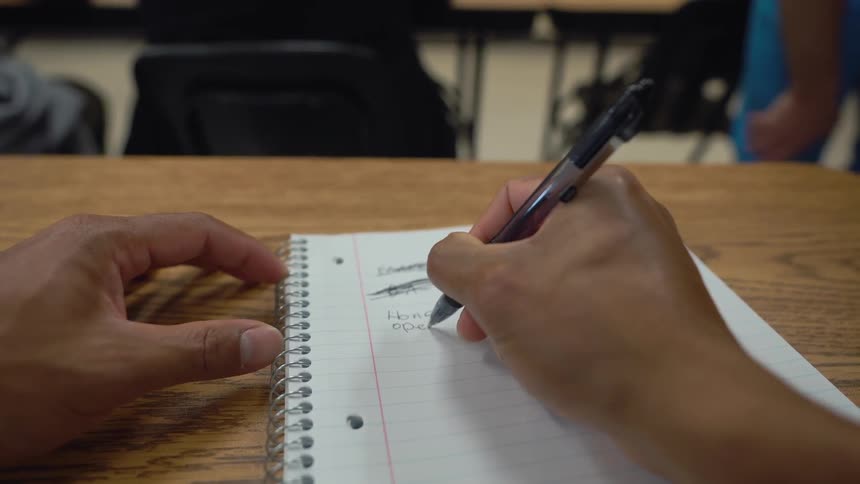Person writing words in a notebook