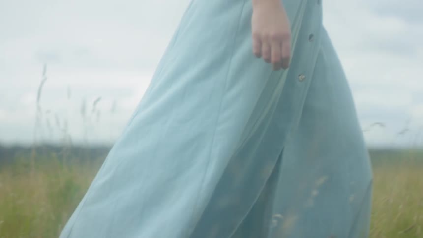 Woman walks barefoot in a grassy field