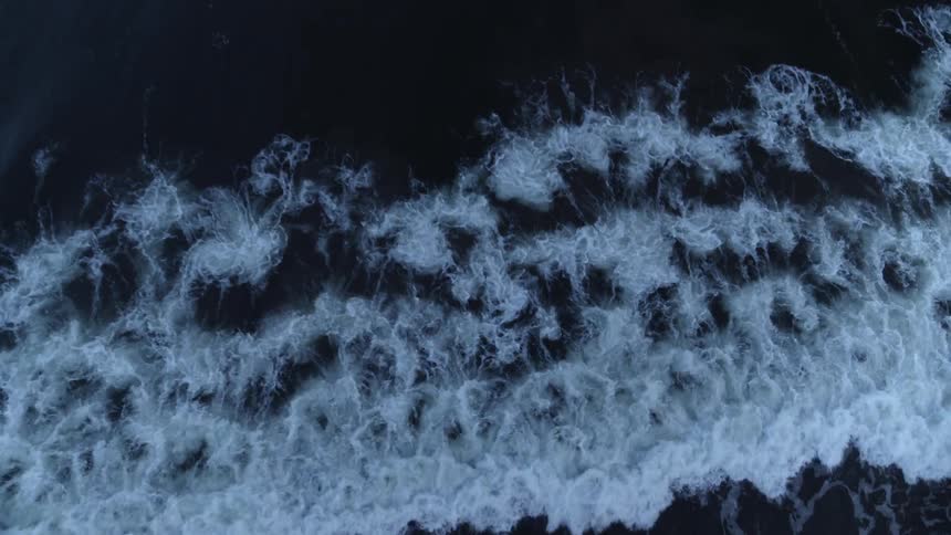 Waves flow onto the shore under cloudy skies