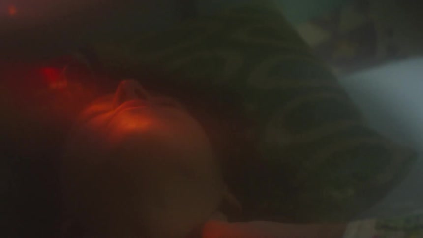 A woman is laying in bed and rubbing her neck