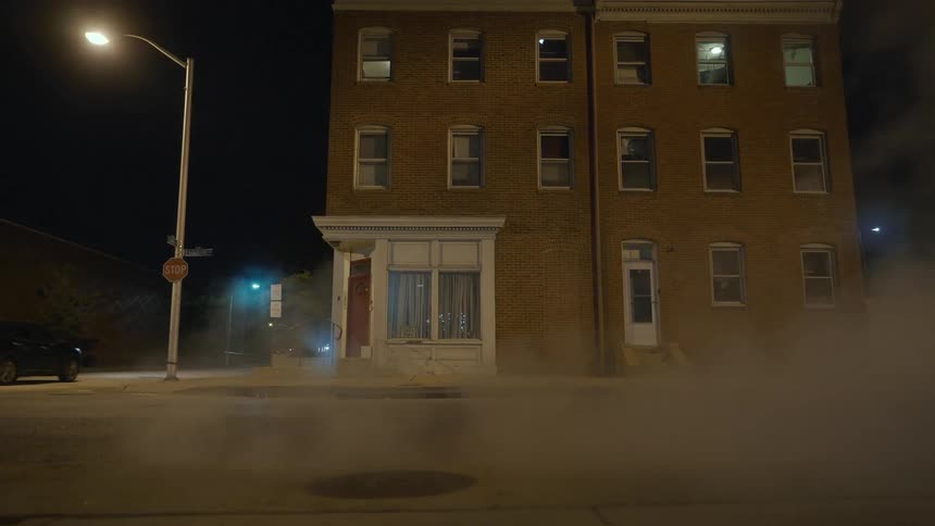 Steam pours from the street at night