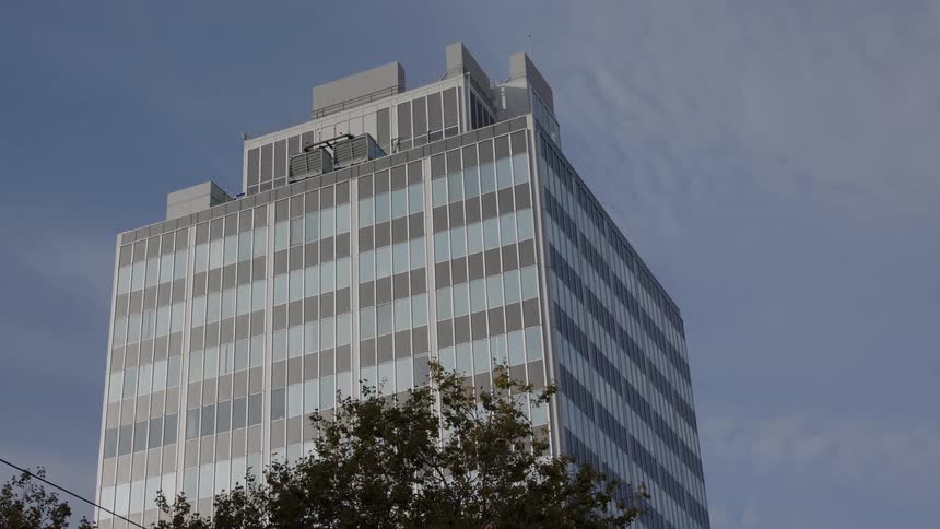 A blue and gray building stands beneath the thin clouds