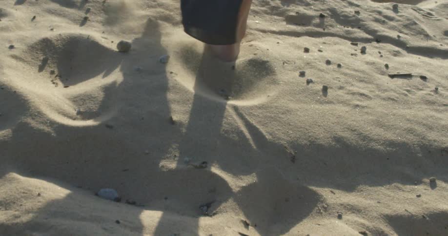 A person walking thru sand