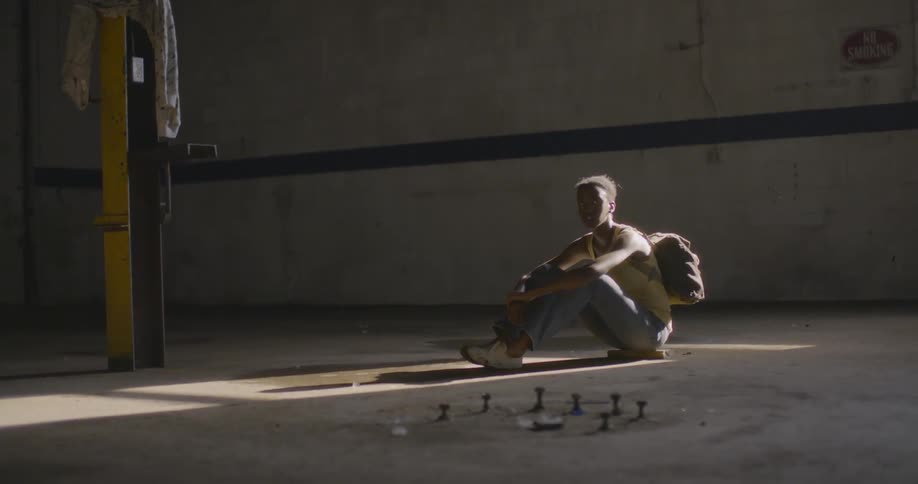 A person in a yellow shirt sits on a concrete floor