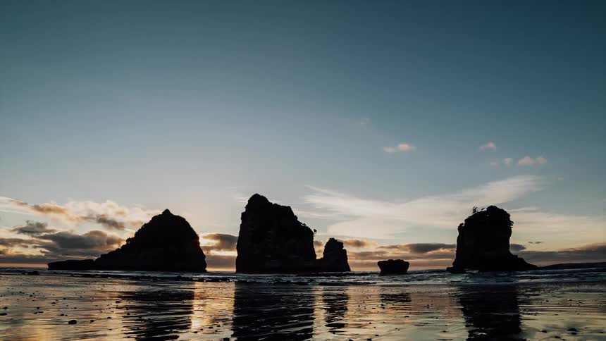 Ocean waves flow around rock formations at sunset