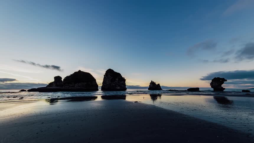 Ocean waves flow around rock formations at sunset