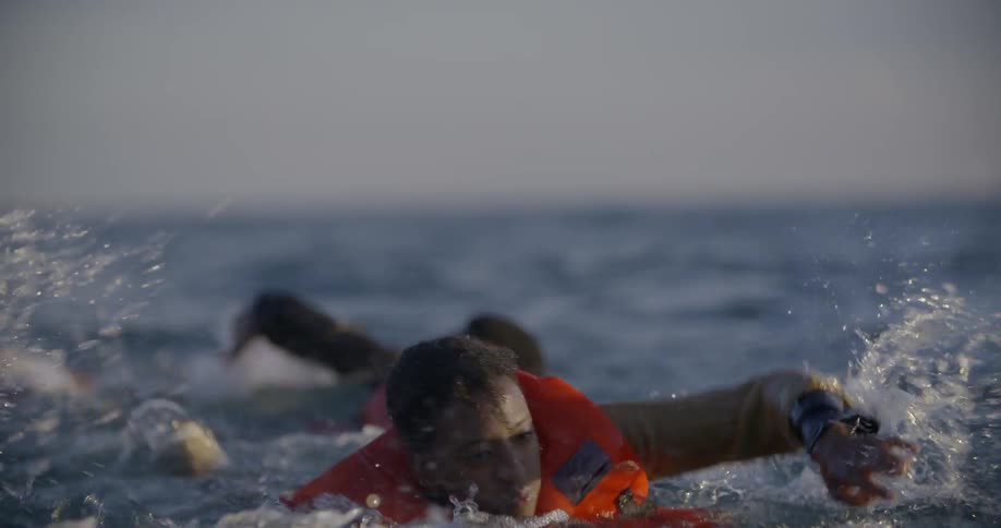 People swim in the ocean while wearing life vests