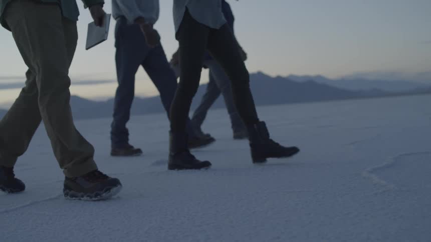People walk across salt flats at sunset