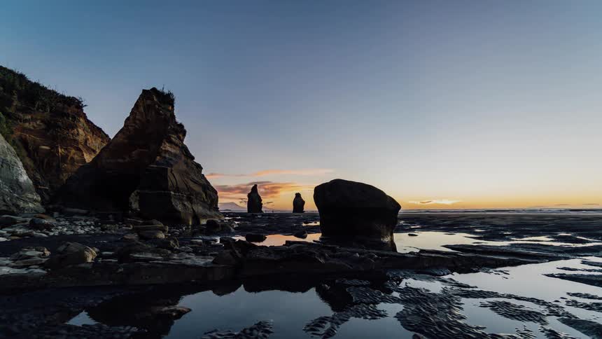 The sun sets over a rocky coastline