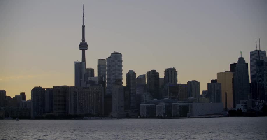 The Toronto skyline is filmed from across a river at dusk